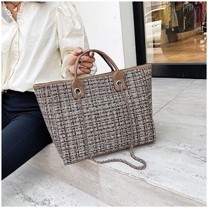 Tweed lattice bucket bag with leather handles and chain strap shown on steps