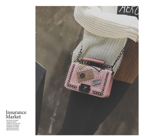 Detailed view of pink quilted crossbody bag with vintage patches and chain strap