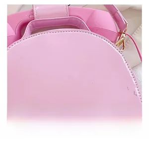 Close-up of pink glossy handbag featuring a unique telephone handset top handle design