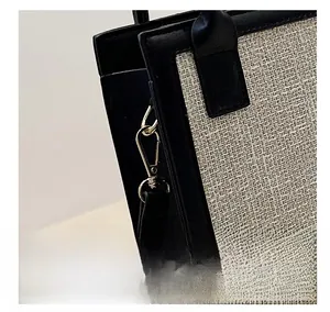 Detailed macro view of the gold-tone metal clasp and D-ring on the woven tote bag