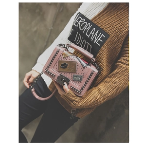 Detail showing pink quilted leather bag with punk patches and metal chain strap