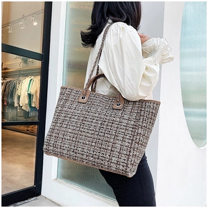 Detail of tweed tote bag with leather handles and chain strap shown on a model