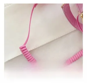 Detail of creative pink glossy handbag with a unique telephone cord spiral handle design