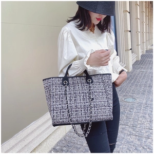 Detailed view of black and white tweed tote bag with silver chain and leather handles