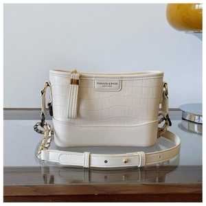 Close-up of cream crocodile pattern leather bucket bag with gold chain and fashion logo