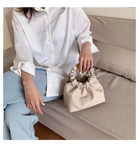 Detail of a creamy pleated cloud bucket bag with soft PU leather textures and folds
