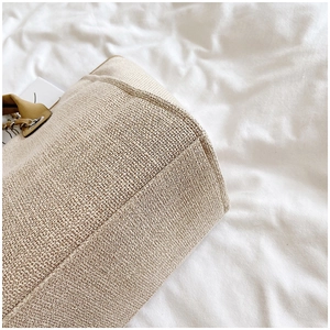 Detailed macro view of woven beige tote bag texture with brown leather handle