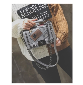 Detail of grey PU leather crossbody bag with vintage chain and metal badge elements