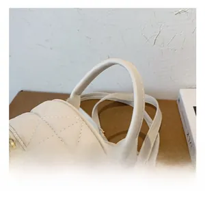 Detail of comfortable handle and gold zipper on white quilted pattern leather bag