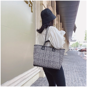 Outdoor shot of the woven plaid tote bag featuring leather trim and chain strap