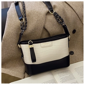 Detail of crocodile pattern texture and metal chain strap on bicolor shoulder bag