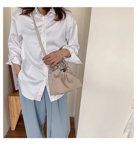 Detail of beige pleated cloud bucket bag with ruffled handle and slim shoulder strap