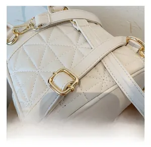 Detail view of white quilted faux leather texture with gold buckle and adjustable strap