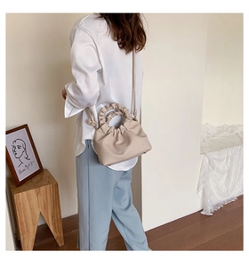 Detail of beige pleated bucket bag with cloud texture and elastic gathered handle