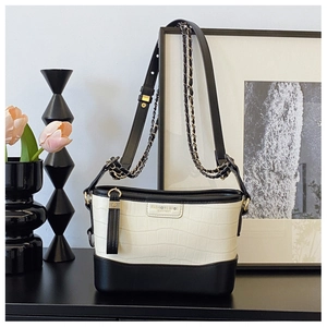Detail of black and white crocodile embossed bucket bag with gold fashion metal logo
