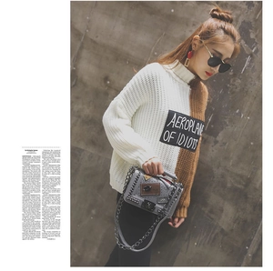 Close-up of grey crossbody bag with metallic studs and badges on a fashion model