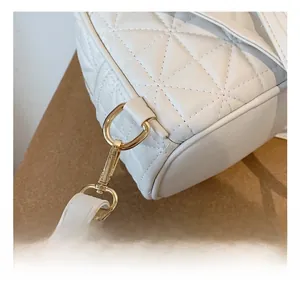 Close-up of white quilted handbag featuring gold D-ring and swivel hook hardware