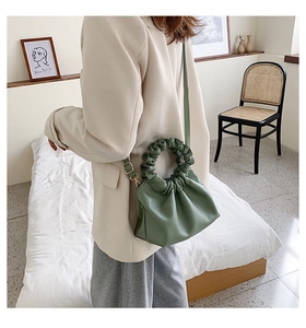 Detail of pea green bucket bag with ruched ring handle and adjustable crossbody strap