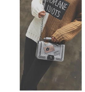 Close-up of grey crossbody bag with silver chains, rivets and vintage patches detail