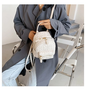Detail of white quilted PU leather mini backpack with gold zippers shown on model