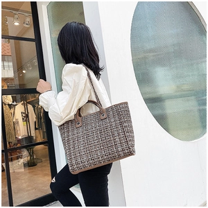 Close-up of brown and white tweed weave texture on a spacious tote bag with chain strap