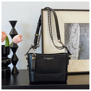 Detailed close-up of crocodile embossed texture on a black crossbody bag with gold hardware