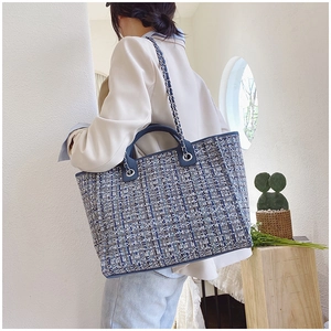 Detail of blue and white tweed bucket bag with metal chain strap and top handle