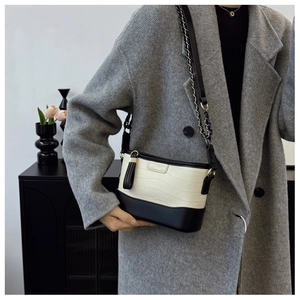 Close-up of stylish crocodile pattern bag featuring gold chain strap and tassel detail