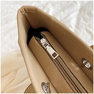 Close-up of khaki suede bucket bag zipper and smooth metal slider on textured fabric