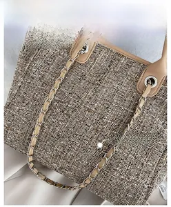 Detail of tweed tote bag showing woven fabric texture and chain shoulder strap