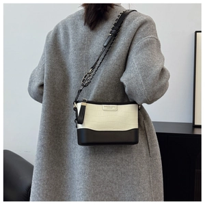 Detail of black and white crocodile texture bucket bag worn with a grey wool coat