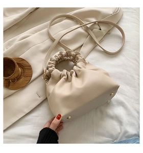 Detail of cream pleated cloud bucket bag with ruched ring handle and metal feet
