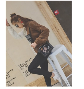 Chic black flap bag with embroidered patches and chain strap styled in autumn outfit