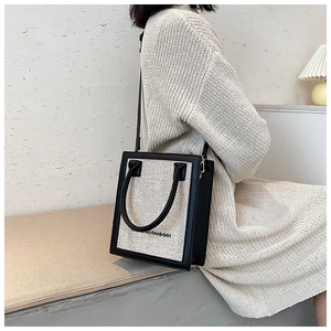 Elegant black and beige panelled crossbody bag styled with a beige knit dress