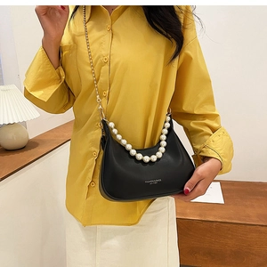 Détail d'un sac demi-lune en cuir noir avec chaîne de perles et bandoulière sur mannequin
