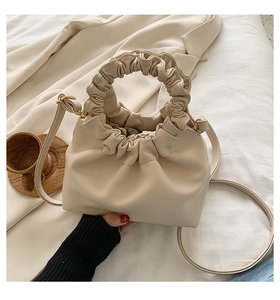 Detail of beige pleated cloud bag showing the unique scrunchie handle and soft leather texture