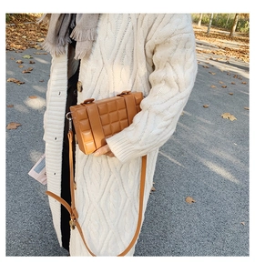 Brown box bag with chocolate texture worn by a model in an outdoor autumn setting