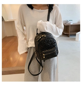 Lifestyle shot of a black quilted mini backpack with gold zippers and PU leather texture