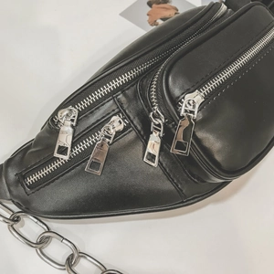 Sac de poitrine polyvalent en cuir noir avec plusieurs zips argentés et chaîne en métal