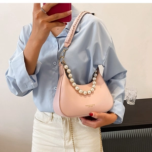 Détail du sac hobo rose clair avec anse en perles et bandoulière tissée sur le côté