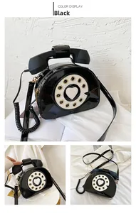 Macro shot of retro black telephone shaped crossbody bag with glossy patent leather finish