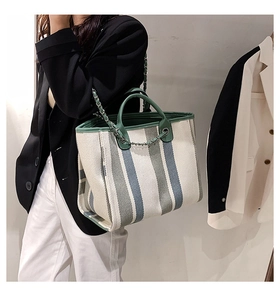Détail d'un sac cabas à rayures en toile avec bordure en cuir vert et chaîne argentée
