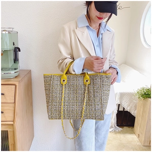 Detail of tweed tote bag with yellow leather trim and silver metal chain strap