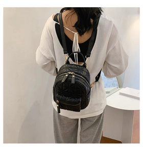Rear view of a model wearing a mini black quilted backpack with star pattern and gold zippers