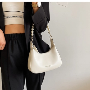 Détail du sac hobo crème avec une élégante bandoulière en perles et garniture dorée
