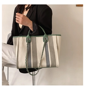 Détail d'un sac seau en toile à rayures avec poignée en PU vert et bandoulière chaîne