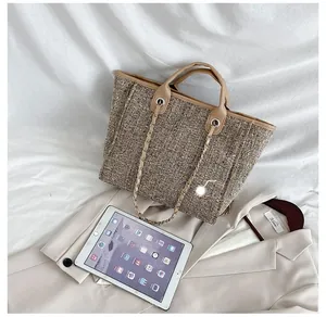 Size comparison of large woven tote bag with a tablet on beige blazer background