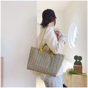 Detail of checkered tweed tote bag with yellow leather trim and gold chain strap
