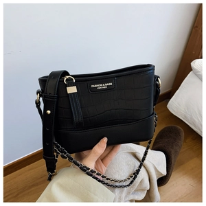 Detail of black crocodile texture leather bag with gold logo and dual shoulder straps