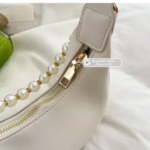 Gros plan sur un sac en cuir blanc avec détails dorés et bandoulière en perles élégantes